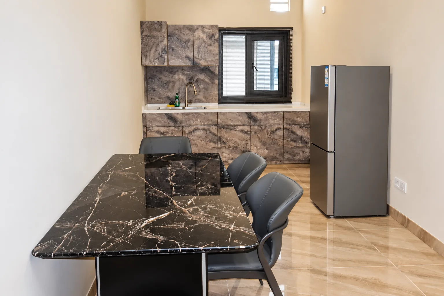 Apartamento de Um Quarto — mesa de jantar em mármore e cozinha com frigorífico de tamanho normal