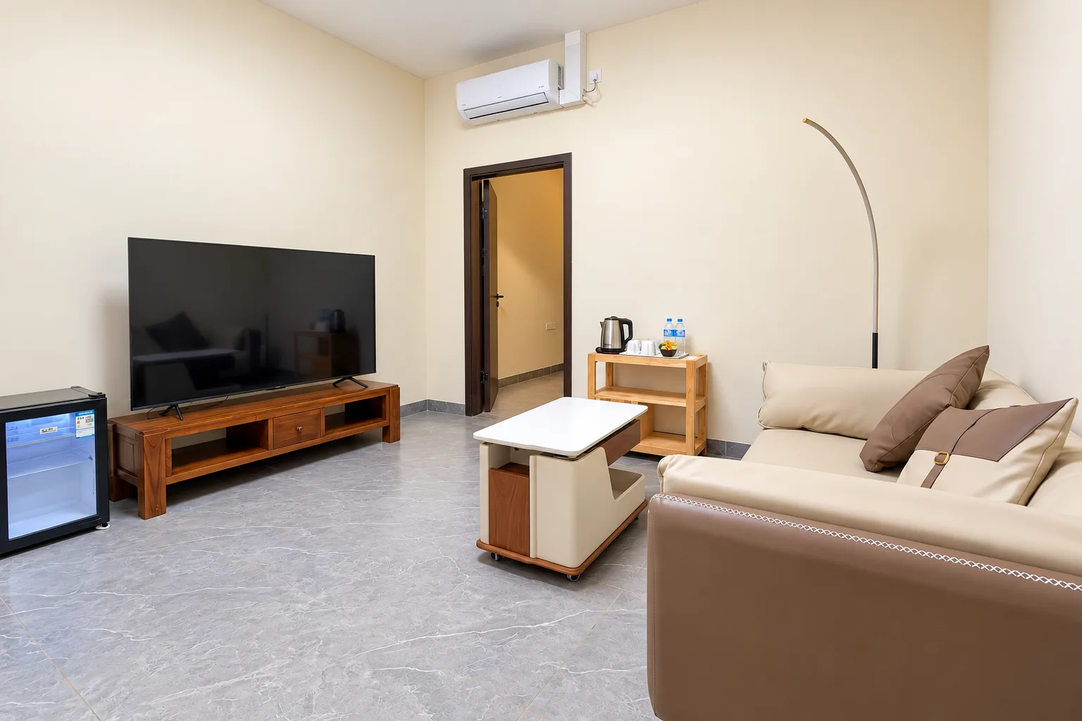 Suite Premium — sala de estar com sofá creme, televisão e minifrigorífico